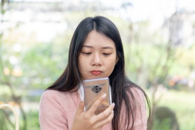30 Ocak 2024 'te Tayvan' ın Tayvan şehrinde Xinyi İlçesi 'nde bir bankta otururken 20' li yaşlarda pembe kazak giyen uzun saçlı bir kadın akıllı telefonuyla konuşuyor..