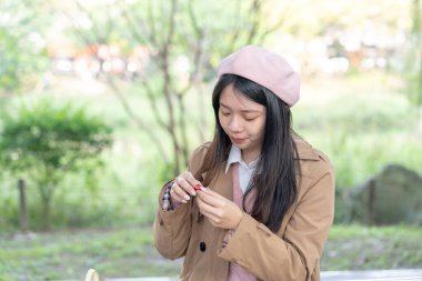 Tayvan 'ın Xinyi İlçesi' ndeki bir bankta oturan, 20 'li yaşlarda kahverengi trençkot giyen, uzun saçlı Tayvanlı bir kadın 30 Ocak 2024' te öğleyin çikolata yer..