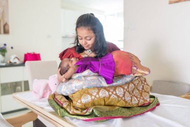 Geleneksel ve sıradan kostümler giyen Hintli bir aile, Malezya 'nın Kuala Lumpur kentindeki yüksek katlı bir apartmanda bebekleri, kızları ve büyükbabalarıyla vakit geçiriyor. Haziran 2024