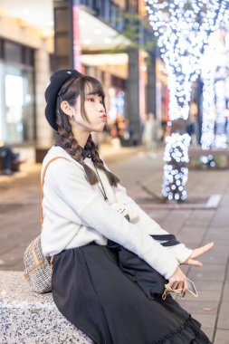 Tayvan 'ın Taipei bölgesindeki Xinyi semtinde bir alışveriş merkezinde gece vakti oturup dinlenen 20' li yaşlarda genç ve tatlı Tayvanlı bir kadın.