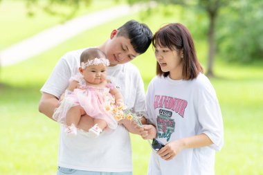 Tayvanlı bir çift 20 'li yaşlarda ve 7 aylık bebekleri Yilan County, Tayvan' da geniş bir yeşil parkta doğum gününü kutluyor..