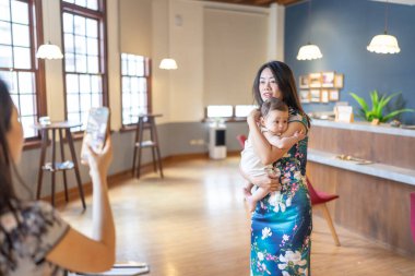 A 6-month-old baby held by a woman in her 30s wearing traditional Chinese clothing inside a building near Dihua Street in Taipei City, Taiwan, in September. clipart