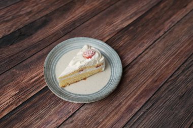 Kahverengi ahşap bir güvertede zarif bir Japon tabağında küçük bir Japon çilekli pasta..