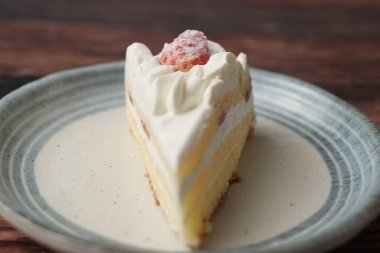 Kahverengi ahşap bir güvertede zarif bir Japon tabağında küçük bir Japon çilekli pasta..