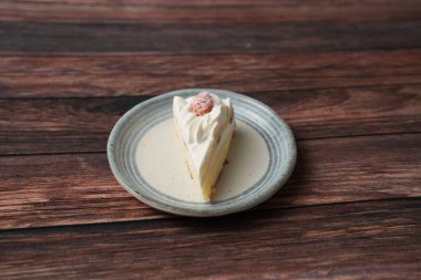 Kahverengi ahşap bir güvertede zarif bir Japon tabağında küçük bir Japon çilekli pasta..