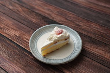 Kahverengi ahşap bir güvertede zarif bir Japon tabağında küçük bir Japon çilekli pasta..