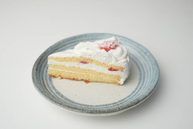 Küçük bir Japon çilekli pastası. Beyaz bir masada, şık bir Japon tabağı üzerinde..