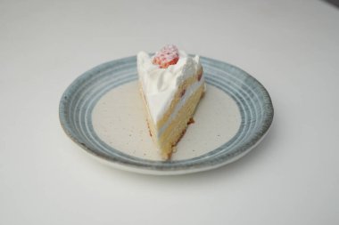 Küçük bir Japon çilekli pastası. Beyaz bir masada, şık bir Japon tabağı üzerinde..