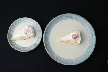 Küçük Japon çilekli çörekleri iki şık Japon stili tabakta, her biri beyaz bir masanın üzerinde siyah bir bez üzerinde..