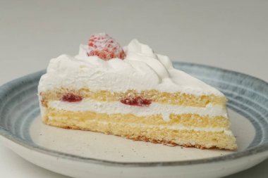 Küçük bir Japon çilekli pastası. Beyaz bir masada, şık bir Japon tabağı üzerinde..