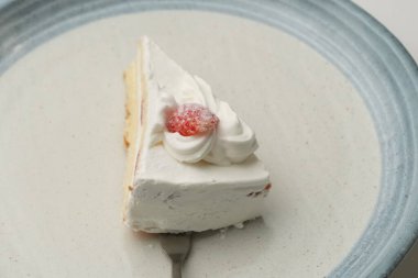 Beyaz bir masada Japon tarzı bir tabakta küçük bir Japon çilekli pasta ve onu kaldırmaya çalışan metal bir spatula..