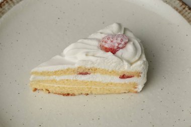 Beyaz bir masada büyük bir tabakta küçük bir Japon çilekli pasta..