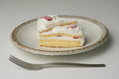 İki Japon çilekli pastası ve beyaz bir masada büyük bir çatal..