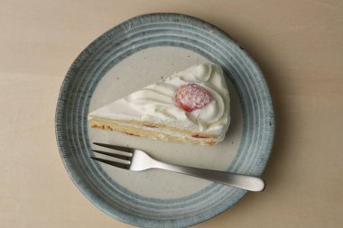 Japon çilekli pastası ve çatalı ahşap bir masadaki her büyük ve küçük tabakta..