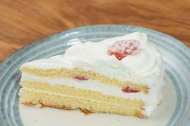 Küçük bir Japon çilekli pastası şık bir Japon tabağı üzerinde siyah bir bez üzerinde beyaz bir masa üzerinde ahşap bir tepside.