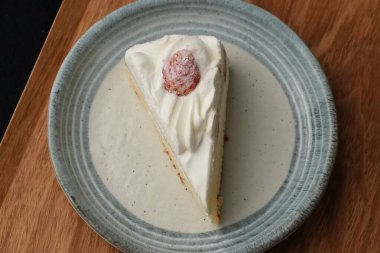 Küçük bir Japon çilekli pastası şık bir Japon tabağı üzerinde siyah bir bez üzerinde beyaz bir masa üzerinde ahşap bir tepside.