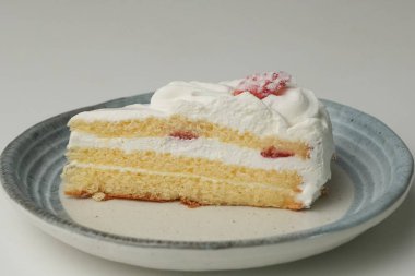 Küçük bir Japon çilekli pastası. Beyaz bir masada, şık bir Japon tabağı üzerinde..