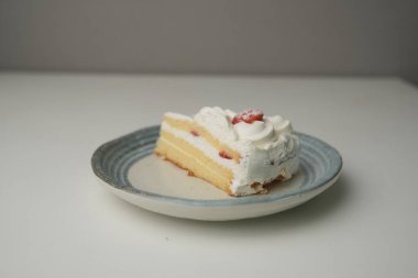 Küçük bir Japon çilekli pastası. Beyaz bir masada, şık bir Japon tabağı üzerinde..
