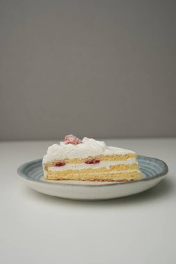 Küçük bir Japon çilekli pastası. Beyaz bir masada, şık bir Japon tabağı üzerinde..
