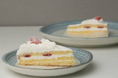 İki Japon çilekli kurabiyesi, biri şık küçük bir tabakta diğeri de büyük bir tabakta, beyaz bir masada..