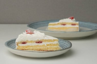 İki Japon çilekli kurabiyesi, biri şık küçük bir tabakta diğeri de büyük bir tabakta, beyaz bir masada..