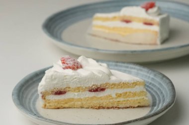 İki Japon çilekli kurabiyesi, biri şık küçük bir tabakta diğeri de büyük bir tabakta, beyaz bir masada..