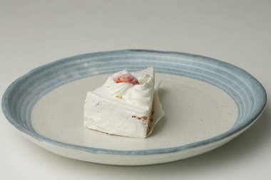 Küçük bir Japon çilekli pastası. Beyaz bir masada, şık bir Japon tabağı üzerinde..