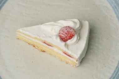 Beyaz bir masada büyük bir tabakta küçük bir Japon çilekli pasta..