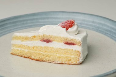 Beyaz bir masada büyük bir tabakta küçük bir Japon çilekli pasta..