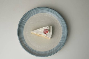 Beyaz bir masada büyük bir tabakta küçük bir Japon çilekli pasta..