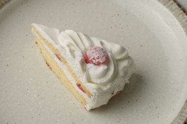 Beyaz bir masada büyük bir tabakta küçük bir Japon çilekli pasta..