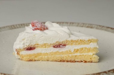 Beyaz bir masada büyük bir tabakta küçük bir Japon çilekli pasta..