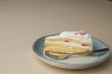 Japon çilekli pastası ve çatalı ahşap bir masadaki her büyük ve küçük tabakta..