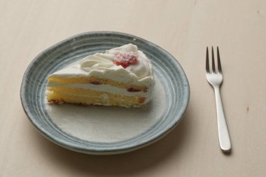 Japon çilekli pastası ve çatalı ahşap bir masadaki her büyük ve küçük tabakta..