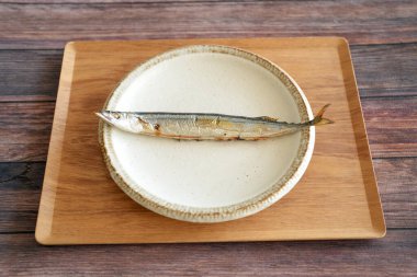 Izgara saury, Japonlar için en önemli sonbahar yemeği, ahşap güvertedeki tepside basit bir tabakta servis edilir..