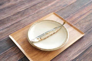 Izgara saury, Japonlar için en önemli sonbahar yemeği, ahşap güvertedeki tepside basit bir tabakta servis edilir..