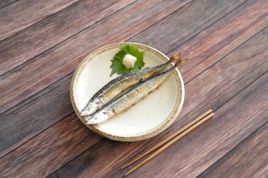 Japonlar için en önemli sonbahar yemeği olan tuzlanmış iki sosis, ahşap bir güvertedeki tepside basit bir tabakta servis edilir. Shiso yaprakları, rendelenmiş daikon turpu ve ahşap çubuklarla servis edilir..