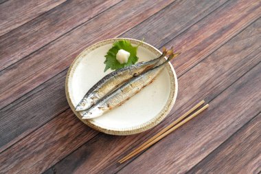 Japonlar için en önemli sonbahar yemeği olan tuzlanmış iki sosis, ahşap bir güvertedeki tepside basit bir tabakta servis edilir. Shiso yaprakları, rendelenmiş daikon turpu ve ahşap çubuklarla servis edilir..