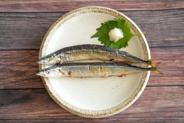Japonlar için en önemli sonbahar yemeği olan tuzlanmış iki sosis, ahşap bir güvertedeki tepside basit bir tabakta servis edilir. Shiso yaprakları, rendelenmiş daikon turpu ve ahşap çubuklarla servis edilir..