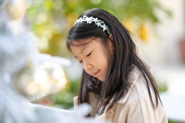 9 yaşındaki Singapurlu bir kadın Çin 'in Şangay şehrindeki güzel bir Noel kafesinde Noel ağacını süslüyor..