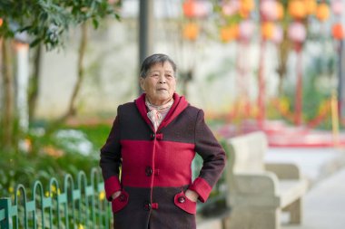 70 'li yaşlarda Çinli bir kadın soğuk kış mevsiminde Qingpu Bölgesi, Şangay, Çin' de bir nehir boyunca yürür..