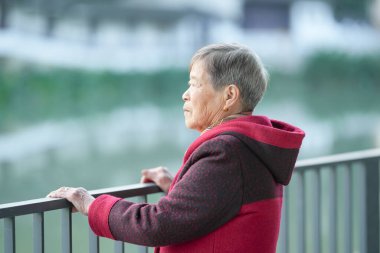 Soğuk bir kış akşamında, 70 'li yaşlarda Çinli bir kadın Çin' in Şangay bölgesindeki Qingpu Bölgesi 'nde bir nehir kıyısında durur..