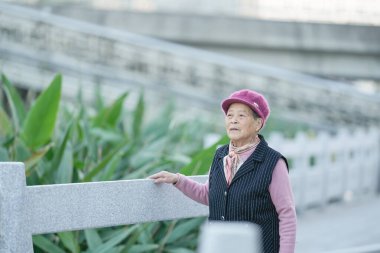 70 'li yaşlarda Çinli bir kadın soğuk kış mevsiminde Qingpu Bölgesi, Şangay, Çin' de bir nehir boyunca yürür..