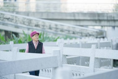 70 'li yaşlarda Çinli bir kadın soğuk kış mevsiminde Qingpu Bölgesi, Şangay, Çin' de bir nehir boyunca yürür..