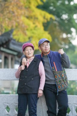 70 'li yaşlarda Çinli bir kadın ve torunu, 30' lu yaşlarda bir adam, Çin 'in soğuk bir kış akşamında Qingpu Bölgesi, Şangay' da nehir kenarında gülümsüyor..