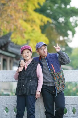 70 'li yaşlarda Çinli bir kadın ve torunu, 30' lu yaşlarda bir adam, Çin 'in soğuk bir kış akşamında Qingpu Bölgesi, Şangay' da nehir kenarında gülümsüyor..