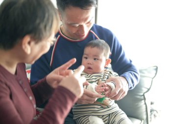 6 aylık Noel kıyafetleri giyen bir çocuk Çin 'de, Pudong Yeni Bölgesi' nde soğuk bir kış gününde Çinli bir aileden gelen babası ve büyükannesiyle birlikte evde vakit geçiriyor..