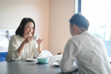 Japon bir çift, 30 'lu yaşlarda bir kadın ve 20' li yaşlarda bir erkek, öğleden sonra evde çay saatinin keyfini çıkarıyorlar..