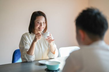 Japon bir çift, 30 'lu yaşlarda bir kadın ve 20' li yaşlarda bir erkek, öğleden sonra evde çay saatinin keyfini çıkarıyorlar..