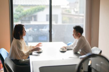 Japon bir çift, 30 'lu yaşlarda bir kadın ve 20' li yaşlarda bir erkek, öğleden sonra evde çay saatinin keyfini çıkarıyorlar..